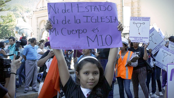 Una niña levanta un cartel que dice: "Ni del estado, ni de la iglesia, el cuerpo es mío."