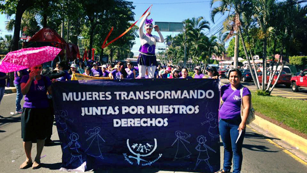 Demonstrationszug mit Mujeres Tranformando Banner und Akrobatin.