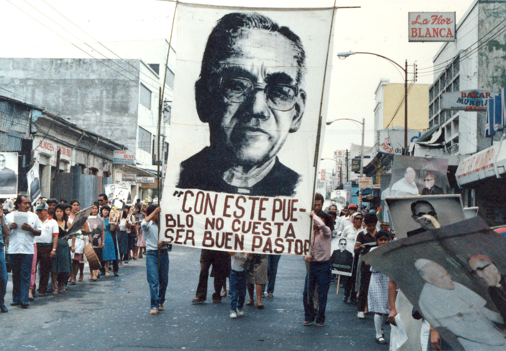 In Gedenken an Oscar Romero trägt ein Demonstrationszug sein Konterfei mit dem Zitat “Mit so einem Volk ist es nicht schwer, ein guter Hirte zu sein” durch eine Straße in El Salvador.
