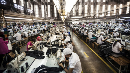 Menschen nähen Kleidung in einer großen Fabrikhalle