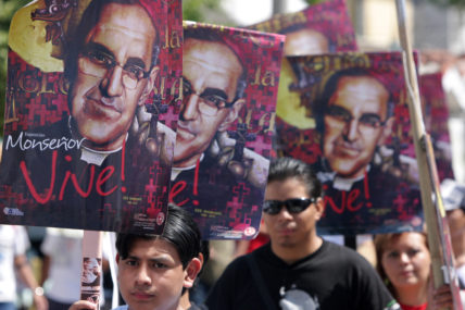 Demo in El Salvador zum 30. Todestag von Oscar Romero, mehrere Menschen halten Plakate mit "Romero lebt"