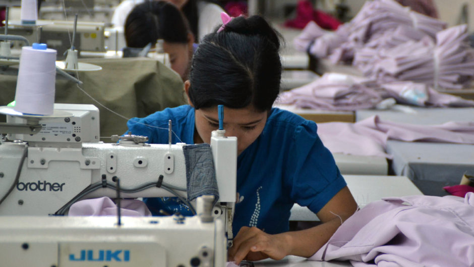 Näherin in einer Fabrik in Myanmar beugt sich über ihre Arbeit