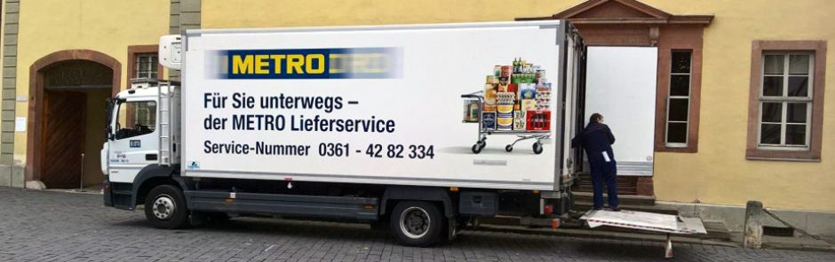 LKW von Metro Großhandel wird entladen, auf dem LKW ist ein voll beladener Einkaufswagen abgedruckt