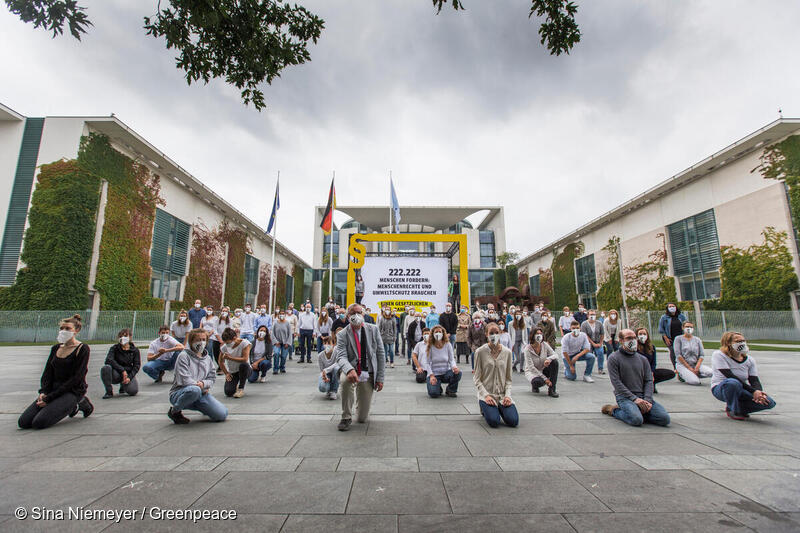 Aktivist*innen knien vor einem symbolischen gesetzlichen Rahmen in Berlin