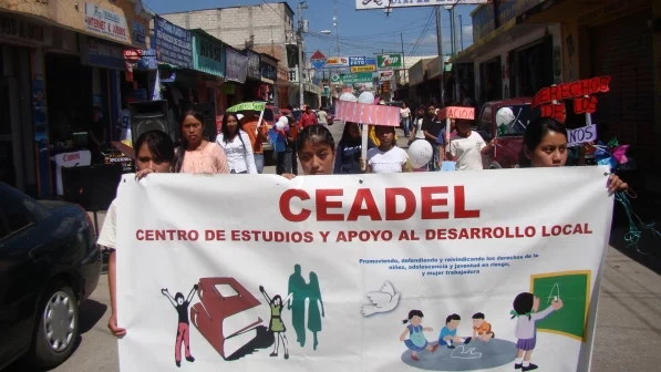 Demonstrierene tragen ein Banner von Ceadel. "Centro de estudios y apoyo al desarrollo local" steht darauf geschrieben.